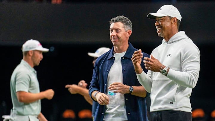 Rory McIlroy and Tiger Woods watch golfers warm up for TGL's inaugural match at SoFi Center.
