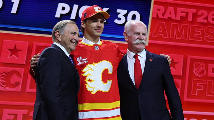 Jun 26, 2026; Buffalo, New York, USA; Jack Hextall reacts beside NHL commissioner Gary Bettman and former NHL player Lanny McDonald after being selected with the thirtieth pick in the first round of the 2026 NHL Draft by the Calgary Flames at KeyBank Center. Mandatory Credit: Timothy T. Ludwig-Imagn Images