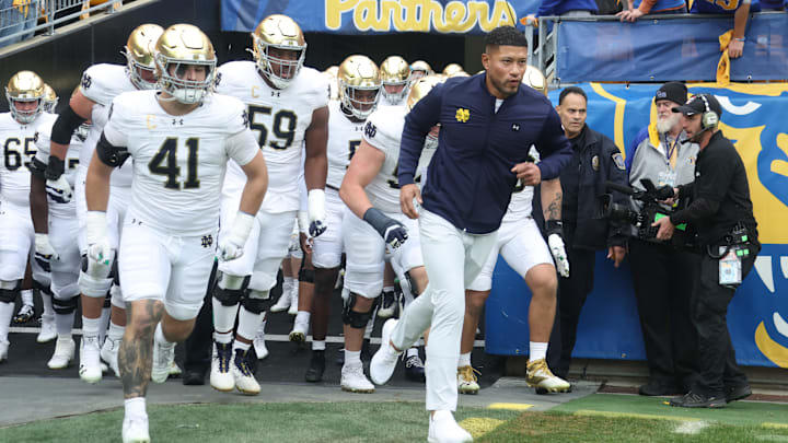 Nov 15, 2025; Pittsburgh, Pennsylvania, USA;  Notre Dame Fighting Irish head coach Marcus Freeman (right) leads the team onto the field to play the Pittsburgh Panthers at Acrisure Stadium. Mandatory Credit: Charles LeClaire-Imagn Images