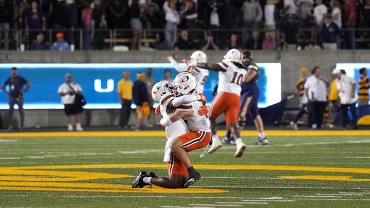 Miami receiver Joshisa Trader (center left) and receiver Xavier Restrepo (center right) celebrate Miiami's win over Cal