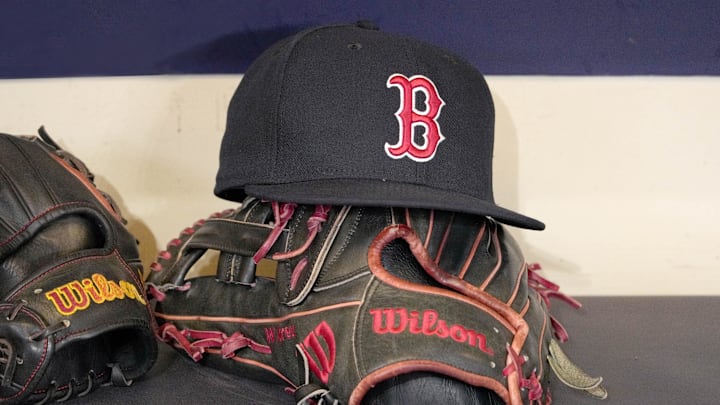 A Boston Red Sox hat and glove sit in the dug out. A Boston Red Sox hat and glove sit in the dug out.