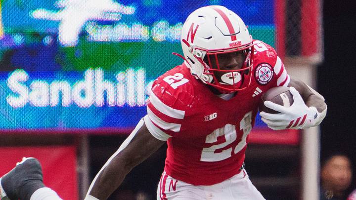 Oct 25, 2025; Lincoln, Nebraska, USA; Nebraska Cornhuskers running back Emmett Johnson (21) runs with the ball against Northwestern Wildcats defensive lineman Carmine Bastone (1) during the third quarter at Memorial Stadium. Mandatory Credit: Dylan Widger-Imagn Images