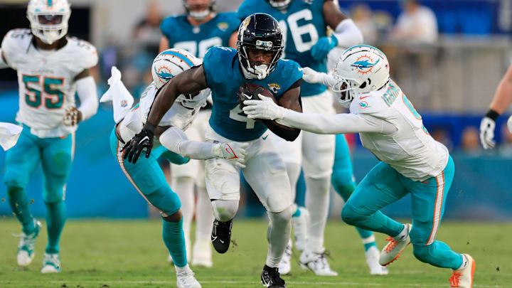 Jacksonville Jaguars running back Tank Bigsby (4) rushes for yards against Miami Dolphins safety Jevon Holland (8) and cornerback Noah Igbinoghene (9) during the second quarter of a preseason matchup Saturday, Aug. 26, 2023 at EverBank Stadium in Jacksonville, Fla. The game was suspended in the fourth after Miami Dolphins wide receiver Daewood Davis (87) was injured on a play with the Jaguars leading 31-18. Jacksonville Jaguars running back Tank Bigsby (4) rushes for yards against Miami Dolphins safety Jevon Holland (8) and cornerback Noah Igbinoghene (9) during the second quarter of a preseason matchup Saturday, Aug. 26, 2023 at EverBank Stadium in Jacksonville, Fla. The game was suspended in the fourth after Miami Dolphins wide receiver Daewood Davis (87) was injured on a play with the Jaguars leading 31-18.