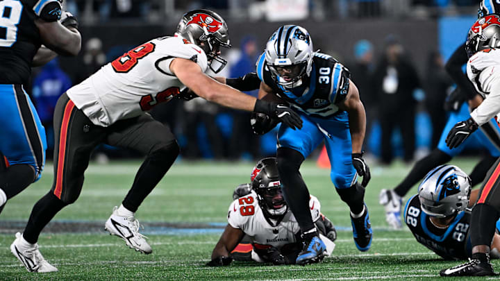 Dec 1, 2024; Charlotte, North Carolina, USA; Tampa Bay Buccaneers linebacker Anthony Nelson (98) stripes Carolina Panthers running back Chuba Hubbard (30) of the ball as safety Christian Izien (29) helps defend in overtime at Bank of America Stadium. Mandatory Credit: Bob Donnan-Imagn Images