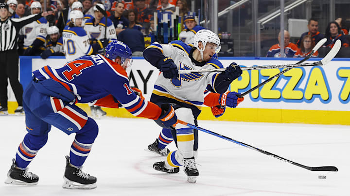 Dec 7, 2024; Edmonton, Alberta, CAN; Edmonton Oilers defensemen Mattias Ekholm (14) knocks a puck away from St. Louis Blues forward Dylan Holloway (81) during the second period at Rogers Place. Mandatory Credit: Perry Nelson-Imagn Images