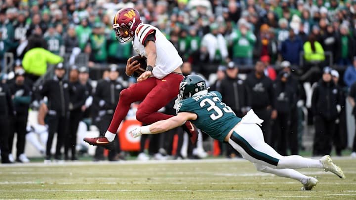 Jan 26, 2025; Philadelphia, PA, USA; Washington Commanders quarterback Jayden Daniels (5) leaps to avoid Philadelphia Eagles cornerback Cooper DeJean (33) during the first half in the NFC Championship game at Lincoln Financial Field. Mandatory Credit: Eric Hartline-Imagn Images