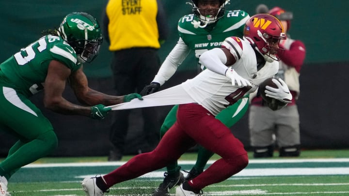 Dec 24, 2023; East Rutherford, NJ;  New York Jets linebacker Quincy Williams (56) holds on to Washington Commanders wide receiver Curtis Samuel (4) in the second half at MetLife Stadium.