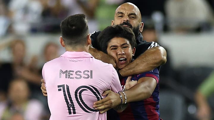 Yassine Chueko apartando a un aficionado que ingresó al campo para tomarse una foto con Lionel Messi