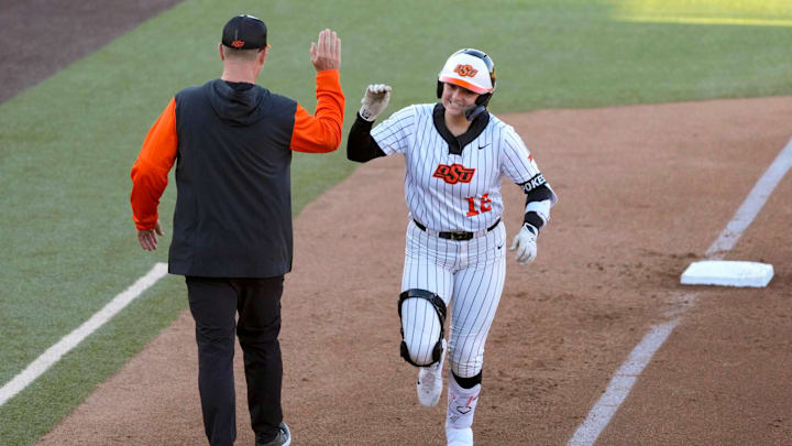 Oklahoma State infielder Micaela Wark (12) celebrates with coach Kenny Gajewski after hitting a two-run homer un in the fourth inning of an NCAA softball game between the Oklahoma State University Cowgirls (OSU) and the Utah Utes in Stillwater, Okla., Friday, May 2, 2025.
