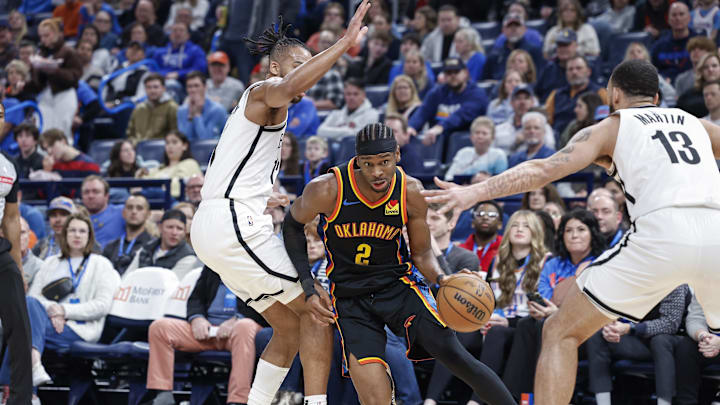 Jan 19, 2025; Oklahoma City, Oklahoma, USA; Oklahoma City Thunder guard Shai Gilgeous-Alexander (2) drives to the basket between Brooklyn Nets forward Tosan Evbuomwan (12) and guard Tyrese Martin (13) during the second half at Paycom Center. Mandatory Credit: Alonzo Adams-Imagn Images Jan 19, 2025; Oklahoma City, Oklahoma, USA; Oklahoma City Thunder guard Shai Gilgeous-Alexander (2) drives to the basket between Brooklyn Nets forward Tosan Evbuomwan (12) and guard Tyrese Martin (13) during the second half at Paycom Center. Mandatory Credit: Alonzo Adams-Imagn Images