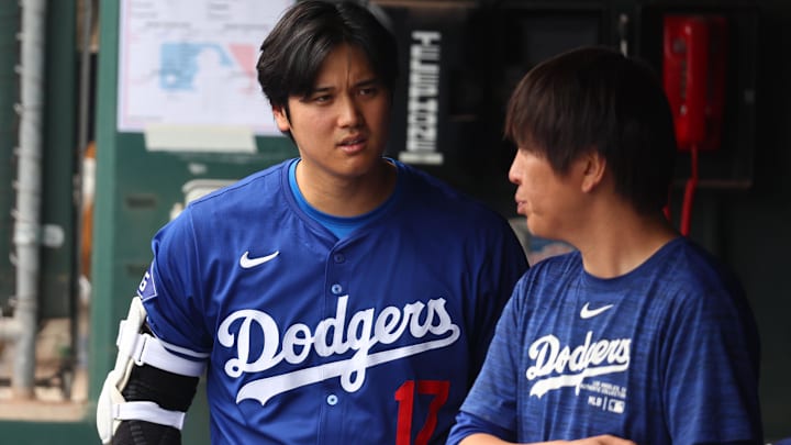 Mar 12, 2024; Phoenix, Arizona, USA; Los Angeles Dodgers designated hitter Shohei Ohtani talks with translator Ippei Mizuhara in the dugout against the San Francisco Giants during a spring training baseball game at Camelback Ranch-Glendale. Mandatory Credit: Mark J. Rebilas-USA TODAY Sports