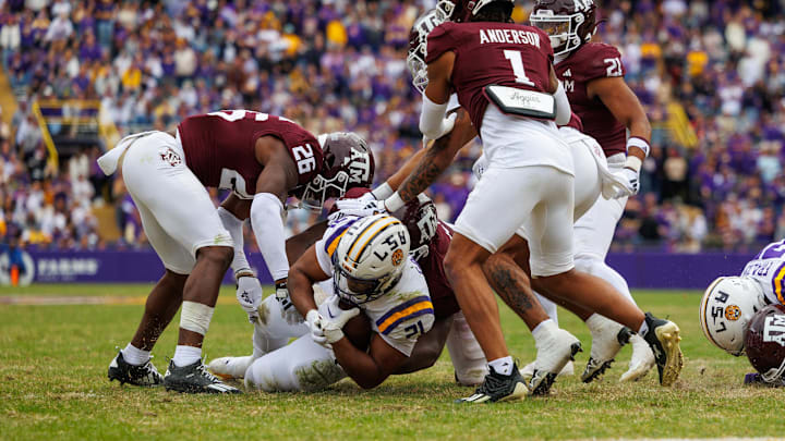 Nov 25, 2023; Baton Rouge, Louisiana, USA;  LSU Tigers running back Noah Cain (21) is tackled by Texas A&M Aggies defensive back Demani Richardson (26) during the second half at Tiger Stadium. Mandatory Credit: Stephen Lew-Imagn Images