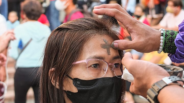 A female devotee receives ash marking on her forehead...