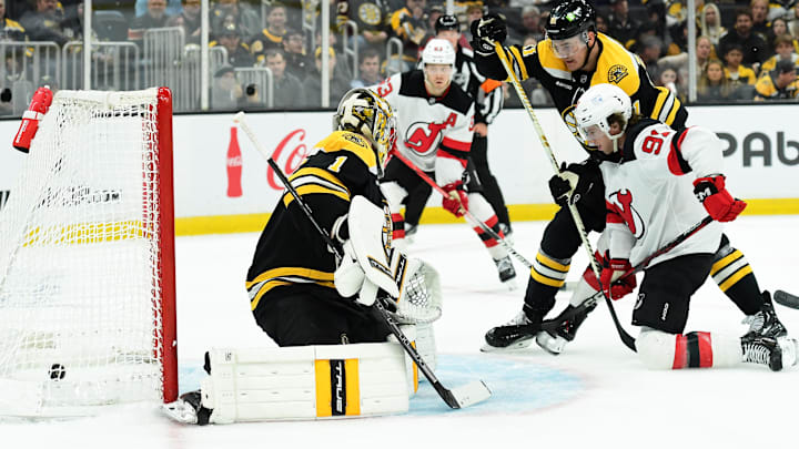 Apr 15, 2025; Boston, Massachusetts, USA;  New Jersey Devils center Dawson Mercer (91) deflects the puck past Boston Bruins goaltender Jeremy Swayman (1) while defenseman Nikita Zadorov (91) defends during the second period at TD Garden. Mandatory Credit: Bob DeChiara-Imagn Images