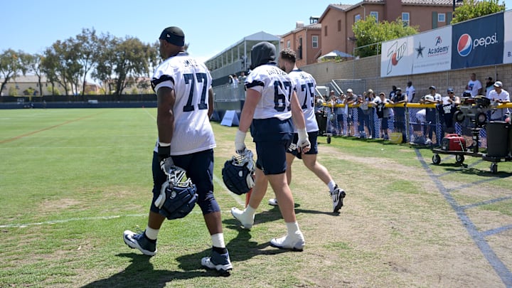 Dallas Cowboys offensive linemen Tyron Smith, Brock Hoffman, and Josh Ball walk onto the field for the first day of training camp.