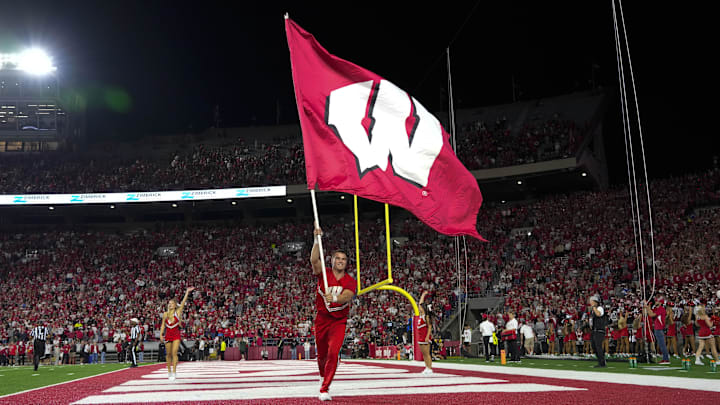 Aug 28, 2025; Madison, Wisconsin, USA;  A Wisconsin Badgers cheerleader carries a Wisconsin flag during the game against the Miami (OH) RedHawks at Camp Randall Stadium.