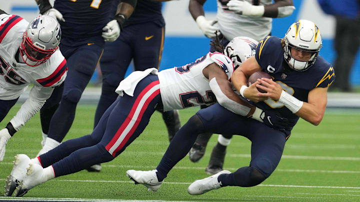 Oct 31, 2021; Inglewood, California, USA; Los Angeles Chargers quarterback Justin Herbert (10) is tackled by New England Patriots defensive back Kyle Dugger (23) n the first half at SoFi Stadium. Mandatory Credit: Kirby Lee-USA TODAY Sports