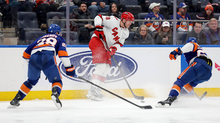 Jan 25, 2025; Elmont, New York, USA; Carolina Hurricanes right wing Mikko Rantanen (96) controls the puck against New York Islanders defenseman Alexander Romanov (28) and center Brock Nelson (29) during the second period at UBS Arena. Mandatory Credit: Brad Penner-Imagn Images