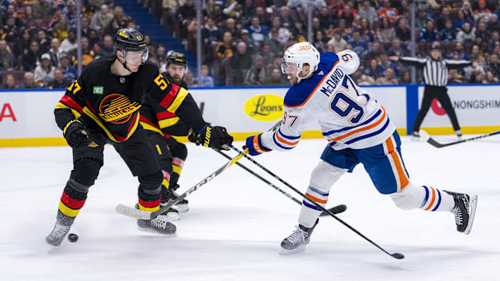 Jan 18, 2025; Vancouver, British Columbia, CAN; Edmonton Oilers forward Connor McDavid (97) shoots around Vancouver Canucks defenseman Tyler Myers (57) in the first period at Rogers Arena. Mandatory Credit: Bob Frid-Imagn Images