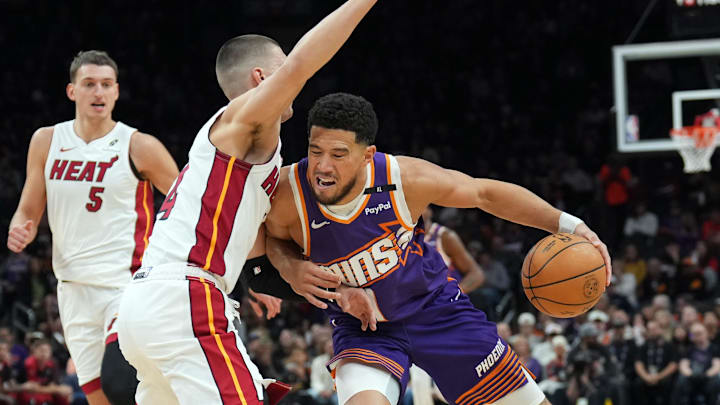 Nov 6, 2024; Phoenix, Arizona, USA; Phoenix Suns guard Devin Booker (1) dribbles against Miami Heat guard Tyler Herro (14) during the first half at Footprint Center. Mandatory Credit: Joe Camporeale-Imagn Images
