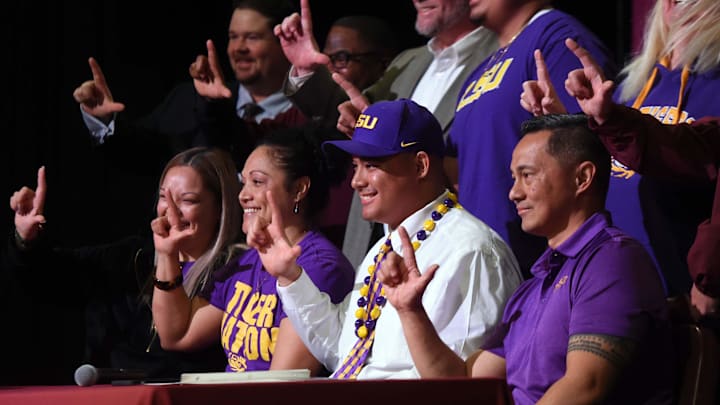 Surrounded by family and his coaches, Kimo Makaneole, center, flashes the L hand gesture during a ceremony at the school Wednesday where he signed to play football with LSU.