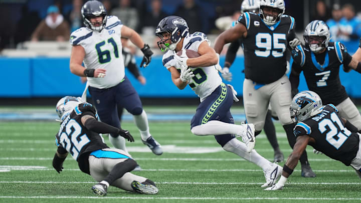 Dec 28, 2025; Charlotte, North Carolina, USA; Seattle Seahawks running back Zach Charbonnet (26) runs the ball against Carolina Panthers safeties Nick Scott (21) and Lathan Ransom (22) during the first quarter at Bank of America Stadium. Mandatory Credit: Jim Dedmon-Imagn Images