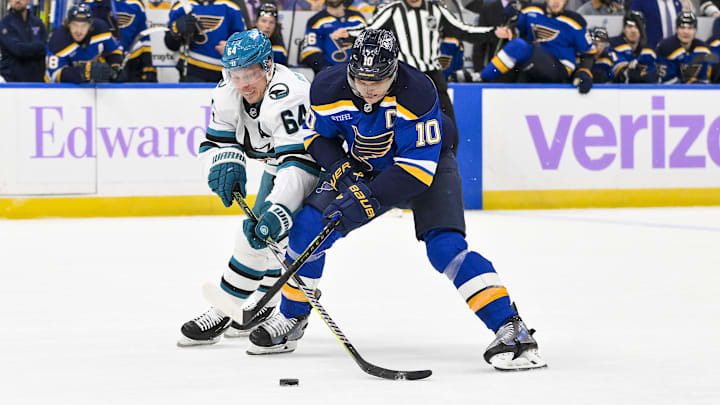 Dec 12, 2024; St. Louis, Missouri, USA;  San Jose Sharks center Mikael Granlund (64) and St. Louis Blues center Brayden Schenn (10) battle for the puck during the second period at Enterprise Center. Mandatory Credit: Jeff Curry-Imagn Images