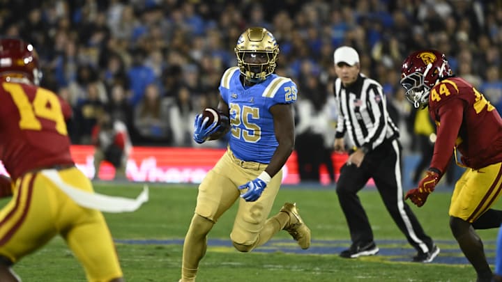 Nov 23, 2024; Pasadena, California, USA; UCLA Bruins running back T.J. Harden (25) runs past USC Trojans defensive end Sam Greene (44) during the first quarter at Rose Bowl. Mandatory Credit: Robert Hanashiro-Imagn Images