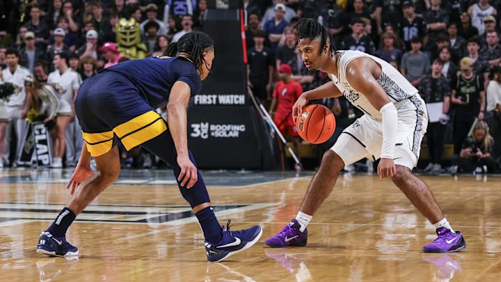 Feb 14, 2026; Orlando, Florida, USA; UCF Knights guard Themus Fulks (1) handles the ball in front of West Virginia Mountaineers guard Jasper Floyd (1) during the second half at Addition Financial Arena. Mandatory Credit: Mike Watters-Imagn Images
