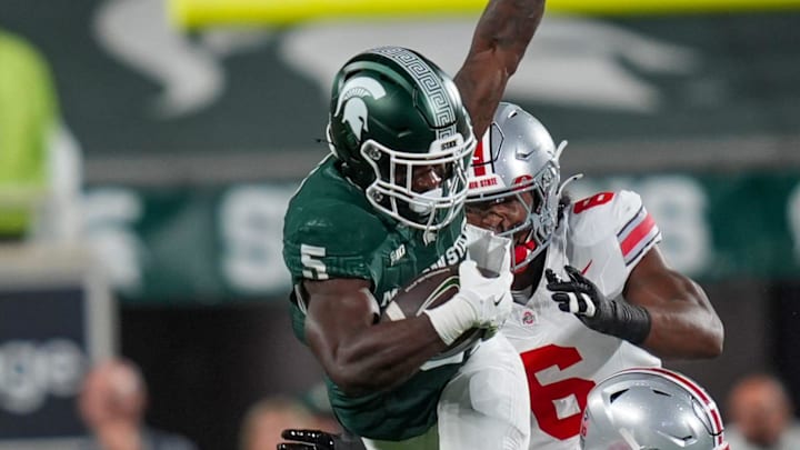 Michigan State Spartans running back Nate Carter (5) is tackled while trying to jump over Ohio State Buckeyes safety Caleb Downs (2) and Ohio State Buckeyes safety Sonny Styles (6) during the first quarter the NCAA football game against Ohio State University at Spartan Stadium in East Lansing, Saturday, Sept. 28, 2024.