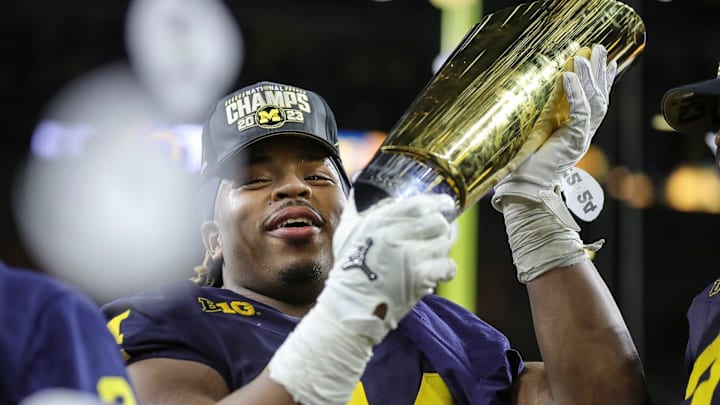 Michigan defensive lineman Kris Jenkins picks up the trophy to celebrate 34-13 win over Washington at the national championship game at NRG Stadium in Houston on Monday, Jan. 8, 2024.
