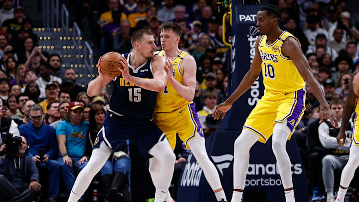 Mar 14, 2025; Denver, Colorado, USA; Denver Nuggets center Nikola Jokic (15) controls the ball as Los Angeles Lakers guard Dalton Knecht (4) guards and center Christian Koloko (10) defends in the fourth quarter at Ball Arena. Mandatory Credit: Isaiah J. Downing-Imagn Images
