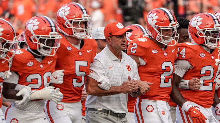 Clemson head coach Dabo Swinney arm-in-arm with defensive back Ronan Hanafin (5) and quarterback Cade Klubnik (2) and teammates during the “Walk of Champions” march to the end zone, before the game with Clemson and Louisiana State University at Memorial Stadium in Clemson, S.C. Saturday, August 30, 2025.