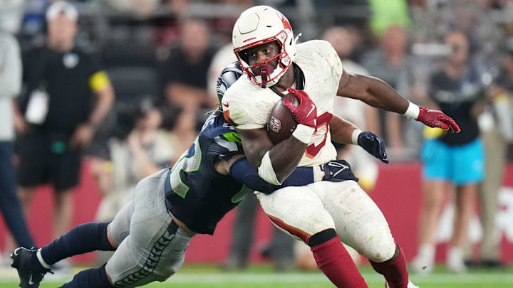 Arizona Cardinals running back Trey Benson (33) tries to break away from Seattle Seahawks linebacker Drake Thomas (42) at State Farm Stadium in Glendale on Sept. 25, 2025.