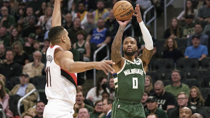 Nov 26, 2023; Milwaukee, Wisconsin, USA;  Milwaukee Bucks guard Damian Lillard (0) shoots against Portland Trail Blazers guard Malcolm Brogdon (11) during the first quarter at Fiserv Forum. Mandatory Credit: Jeff Hanisch-Imagn Images