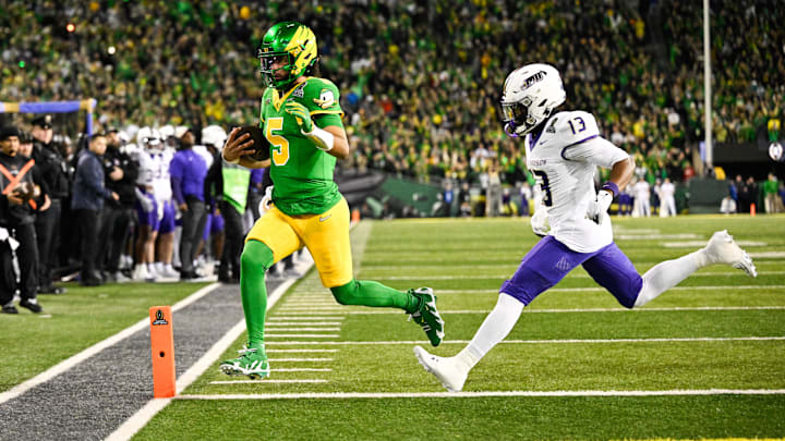 Dec 20, 2025; Eugene, OR, USA; Oregon Ducks quarterback Dante Moore (5) rushes for a touchdown as James Madison Dukes safety Tyler Brown (13) defends during the first quarter at Autzen Stadium. Mandatory Credit: Troy Wayrynen-Imagn Images