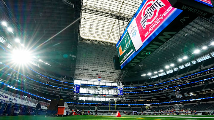Logos for the Ohio State Buckeyes and Miami Hurricanes are displayed on the giant video board prior to the Cotton Bowl at AT&T Stadium in Arlington, Texas for the College Football Playoff quarterfinal game on Dec. 31, 2025.
