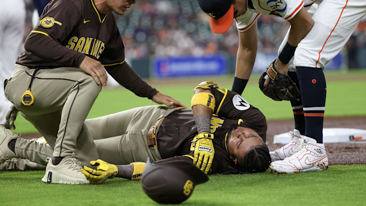 Apr 20, 2025; Houston, Texas, USA;San Diego Padres first base coach David Macias (46) and Houston Astros second baseman Mauricio Dubon (14) check on San Diego Padres designated hitter Luis Arraez (4) as he  lies on the field after colliding with Houston Astros first baseman Christian Walker (8) (not pictured )on the first base line  in the first inning  at Daikin Park. Mandatory Credit: Thomas Shea-Imagn Images