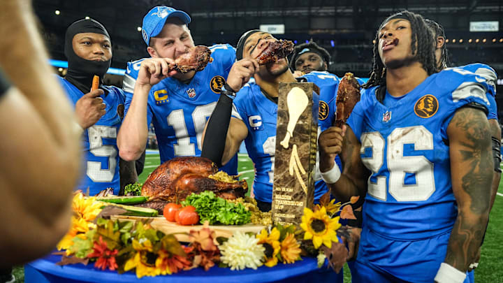 Lions quarterback Jared Goff (16), defensive tackle DJ Reader (98), wide receiver Amon-Ra St. Brown (14), running back Jahmyr Gibbs (26) and linebacker Al-Quadin Muhammad (69) celebrate their win against the Bears with a turkey drumstick Thanksgiving Day in Detroit.