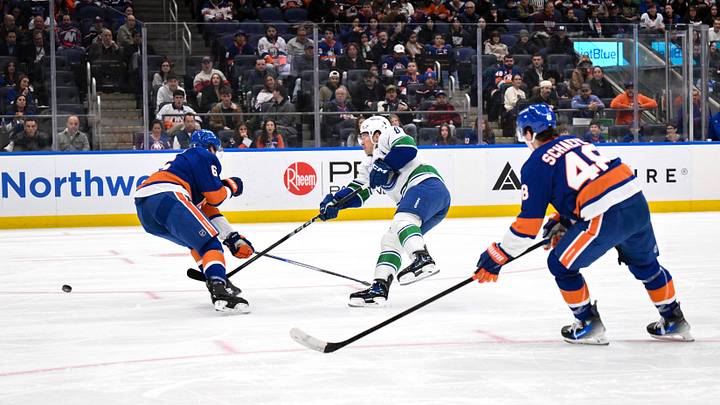 Dec 19, 2025; Elmont, New York, USA; Vancouver Canucks right wing Brock Boeser (6) passes the puck while defended by New York Islanders defenseman Ryan Pulock (6) during the first period at UBS Arena. Mandatory Credit: John Jones-Imagn Images