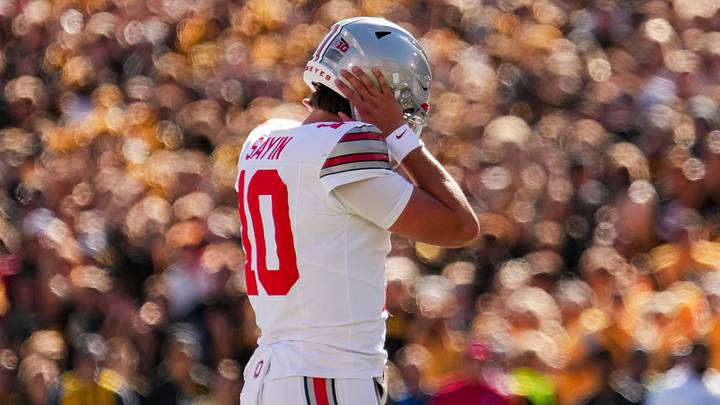 Ohio State Buckeyes quarterback Julian Sayin (10) covers his ears to hear the play call during the NCAA football game against the Iowa Hawkeyes at Kinnick Stadium in Iowa City on Oct. 3, 2026. Ohio State Buckeyes quarterback Julian Sayin (10) covers his ears to hear the play call during the NCAA football game against the Iowa Hawkeyes at Kinnick Stadium in Iowa City on Oct. 3, 2026.