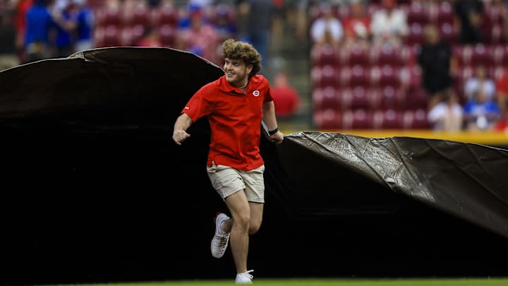 May 26, 2024; Cincinnati, Ohio, USA; A member of the Cincinnati Reds grounds crew pulls the tarp on the field at the start of a rain delay in the sixth inning in the game between the Los Angeles Dodgers and the Cincinnati Reds at Great American Ball Park. Mandatory Credit: Katie Stratman-USA TODAY Sports