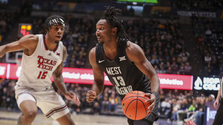 Feb 8, 2026; Morgantown, West Virginia, USA; West Virginia Mountaineers guard Chance Moore (13) dribbles along the baseline against Texas Tech Red Raiders forward JT Toppin (15) during the second half at Hope Coliseum. 