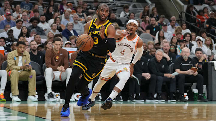 Mar 31, 2024; San Antonio, Texas, USA;  Golden State Warriors guard Chris Paul (3) dribbles past San Antonio Spurs guard Devonte' Graham (4) in the first half at Frost Bank Center. Mandatory Credit: Daniel Dunn-Imagn Images