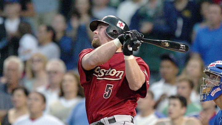 Former Houston Astros player Jeff Bagwell swings the bat wearing a red jersey and black helmet. 