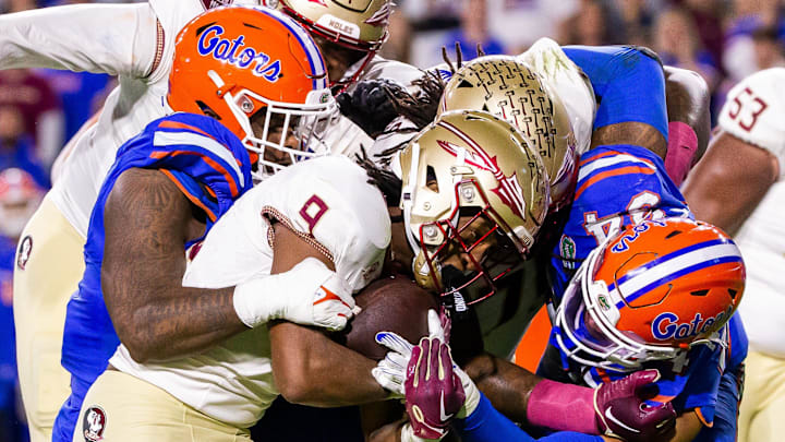 Florida State Seminoles running back Lawrance Toafili (9) is tackled by Florida Gators linebacker Mannie Nunnery (34) and another teammate at Steve Spurrier Field at Ben Hill Griffin Stadium in Gainesville, FL on Saturday, November 25, 2023 during the first half. [Doug Engle/Gainesville Sun]
