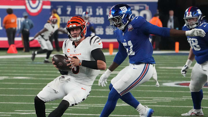 Oct 13, 2024; East Rutherford, New Jersey, USA;  Cincinnati Bengals quarterback Joe Burrow (9) is chased by New York Giants linebacker Azeez Ojulari (51) during the first half at MetLife Stadium. Mandatory Credit: Robert Deutsch-Imagn Images