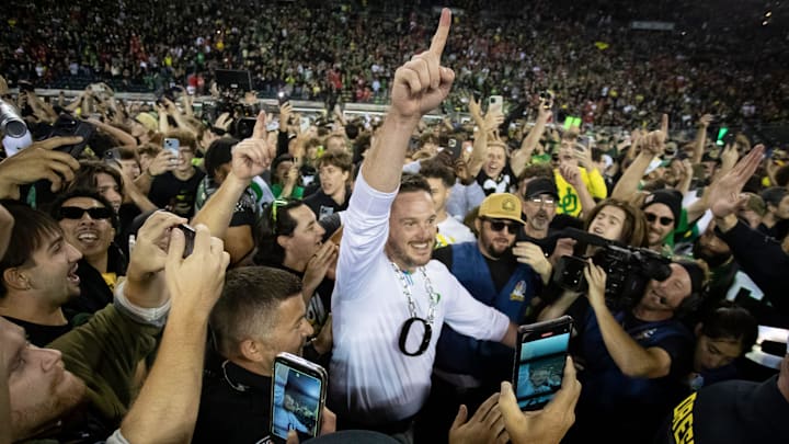Coach Dan Lanning celebrates amid a crowd of fans on the field as No. 3 Oregon knocked off No. 2 Ohio State 