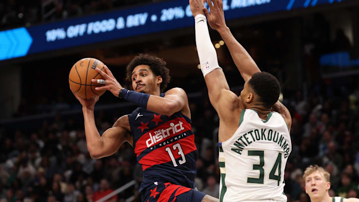 Feb 21, 2025; Washington, District of Columbia, USA; Washington Wizards guard Jordan Poole (13) leaps to pass the ball as Milwaukee Bucks forward Giannis Antetokounmpo (34) defends in the second half at Capital One Arena. Mandatory Credit: Geoff Burke-Imagn Images