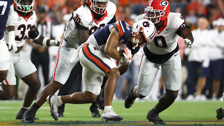 Oct 11, 2025; Auburn, Alabama, USA;  Auburn Tigers running back Jeremiah Cobb (23) carries as Georgia Bulldogs linebacker Terrell Foster (30) and linebacker Gabe Harris Jr. (0) close in during the first quarter at Jordan-Hare Stadium. Mandatory Credit: John Reed-Imagn Images Oct 11, 2025; Auburn, Alabama, USA;  Auburn Tigers running back Jeremiah Cobb (23) carries as Georgia Bulldogs linebacker Terrell Foster (30) and linebacker Gabe Harris Jr. (0) close in during the first quarter at Jordan-Hare Stadium. Mandatory Credit: John Reed-Imagn Images